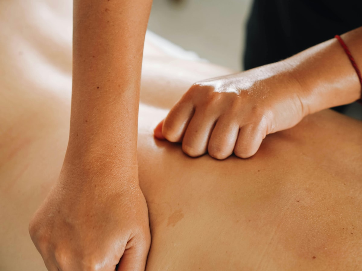 A therapist using light strokes along a client's back
