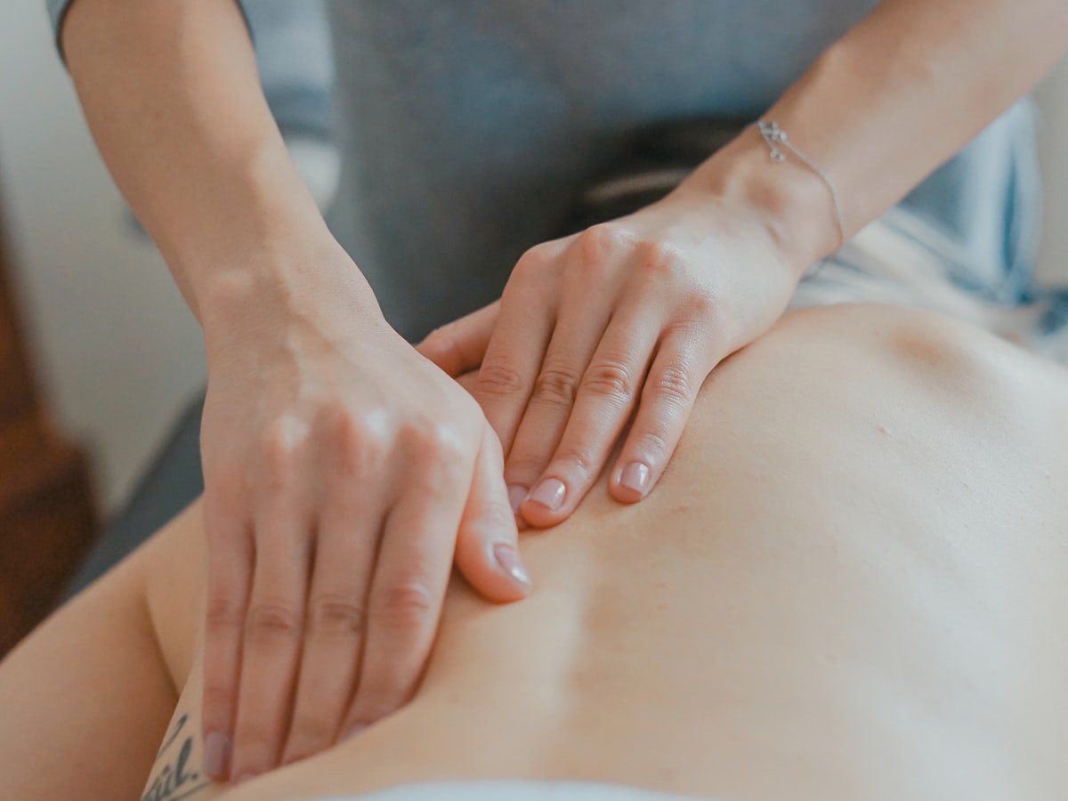A therapist working across a client's upper back